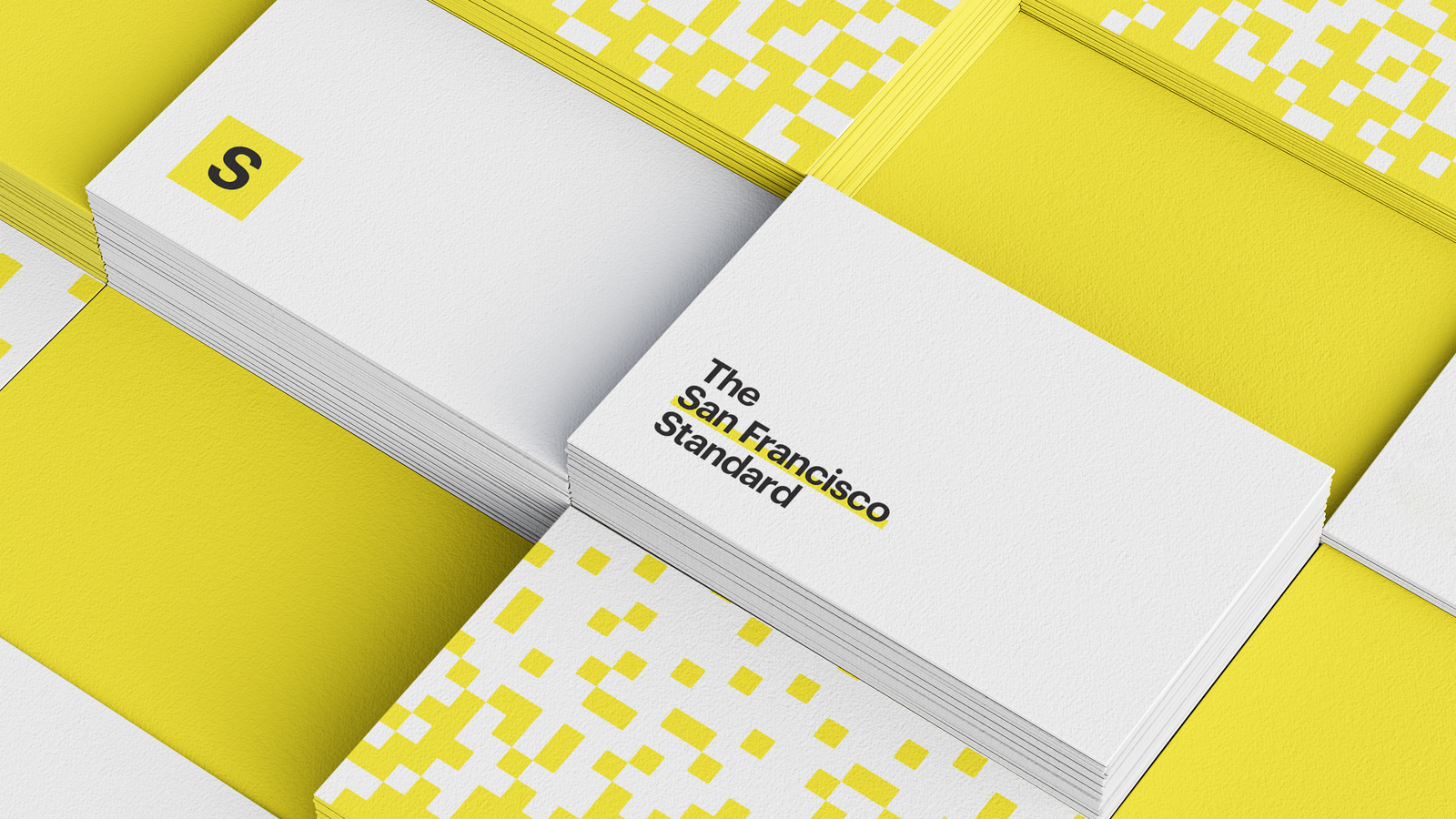 Stationery — business cards stacked on a yellow surface with the pixelation motif and the wordmark.